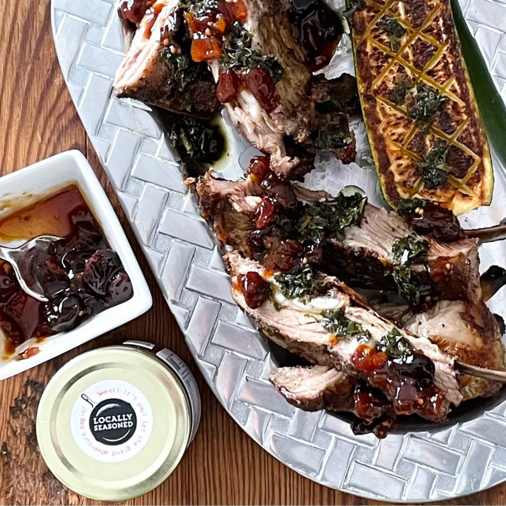 Carved roasted lamb breast with herb oil & Cherry Jalapeno Chutney on a pewter platter.