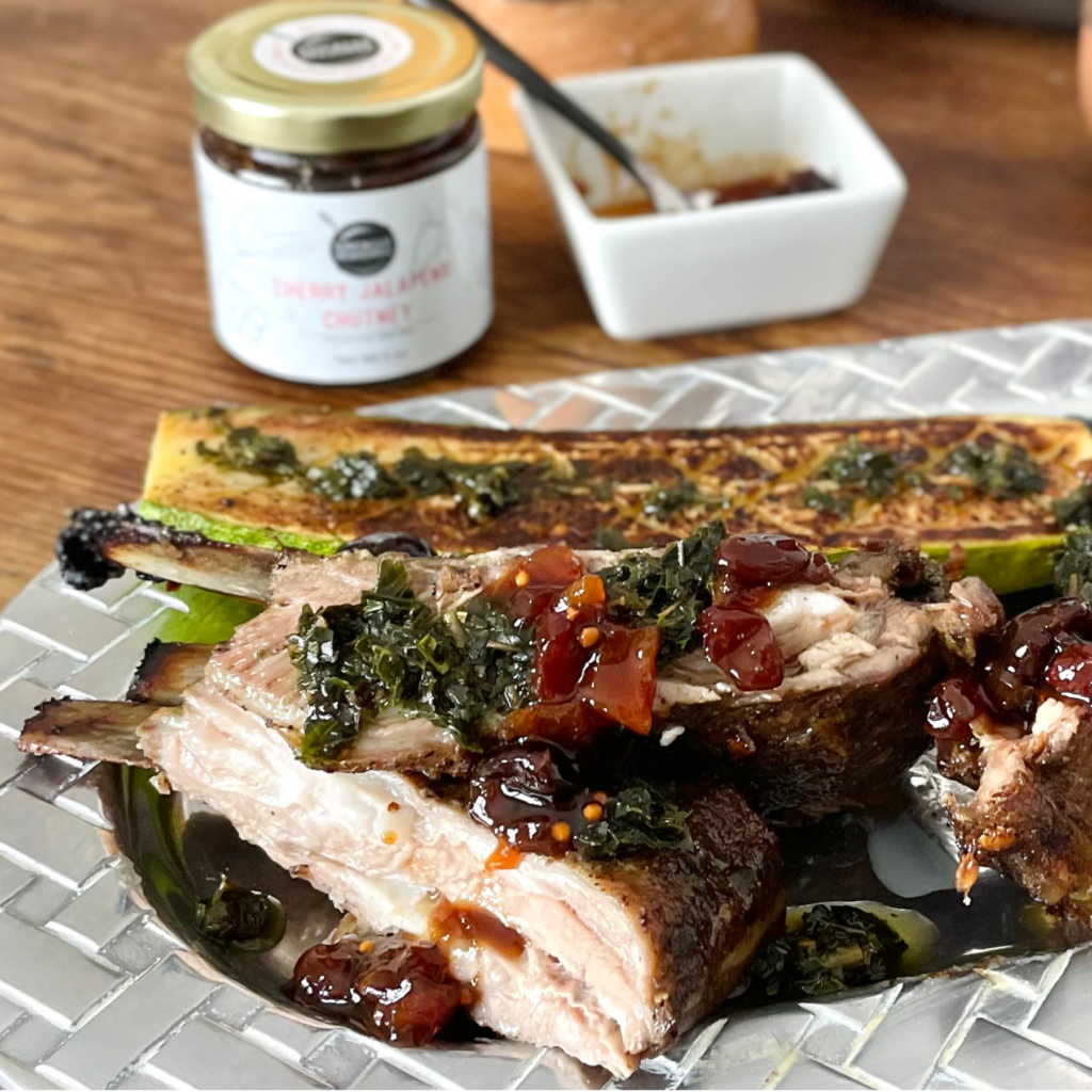 Roasted lamb breast carved on a pewter platter with grilled zucchini. Topped with herb oil and Cherry Jalapeno Chutney.